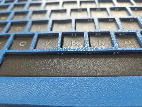 Cloase up of a blue keyguard with shallow key spaces on a keyboard