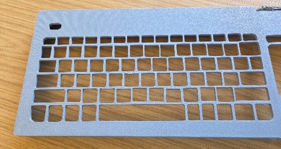Grey plastic keyguard labelled version 2 on a wooden surface.