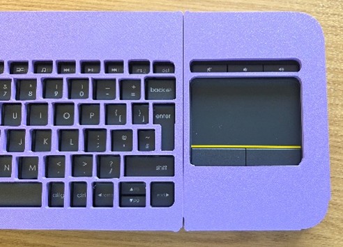 Purple plastic keyguard on a keyboard sitting on a wooden surface.