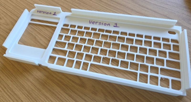 White plastic keyguard labelled version 1 on a wooden surface.