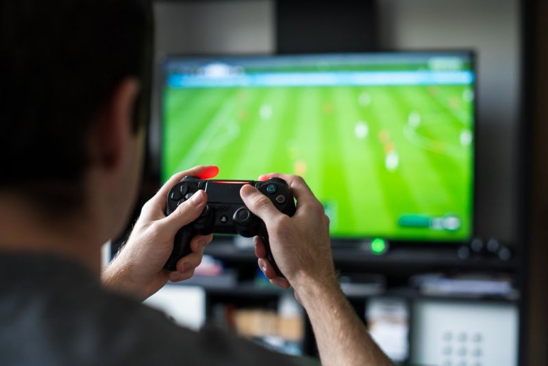 A view over the soulder of a man playing a football video game.